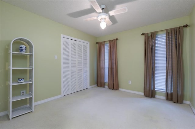 unfurnished bedroom with a textured ceiling, ceiling fan, a closet, and light carpet