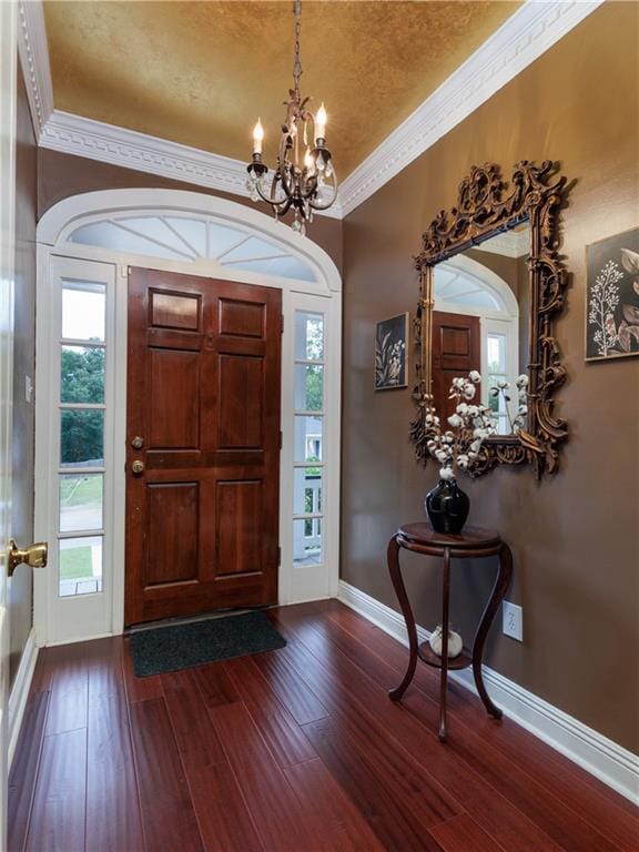 foyer entrance featuring ornamental molding, wood-type flooring, and a notable chandelier