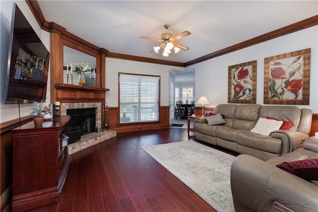 living room featuring a fireplace, dark wood-type flooring, crown molding, and ceiling fan