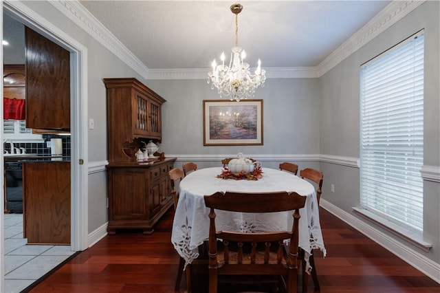 dining space with crown molding, an inviting chandelier, and dark hardwood / wood-style floors