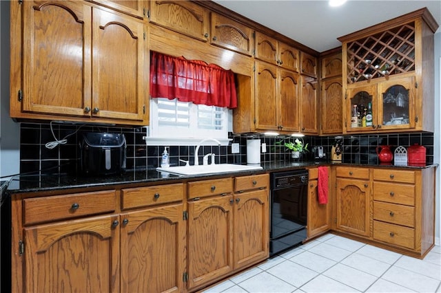 kitchen with dark stone countertops, light tile patterned floors, black dishwasher, and tasteful backsplash