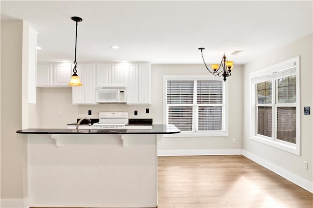 kitchen featuring a breakfast bar area, white cabinets, decorative light fixtures, and white appliances