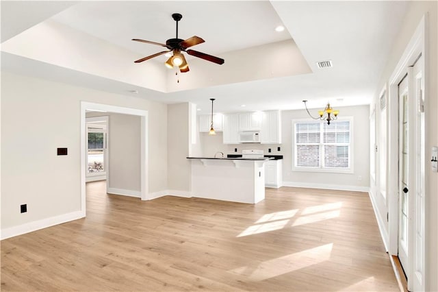 unfurnished living room with ceiling fan with notable chandelier and light hardwood / wood-style floors