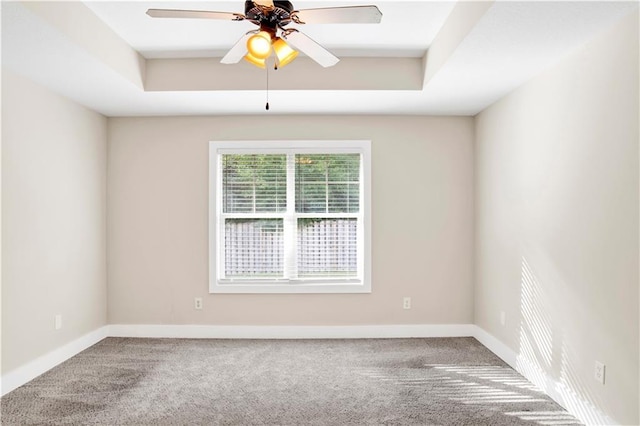 carpeted spare room featuring a tray ceiling and ceiling fan