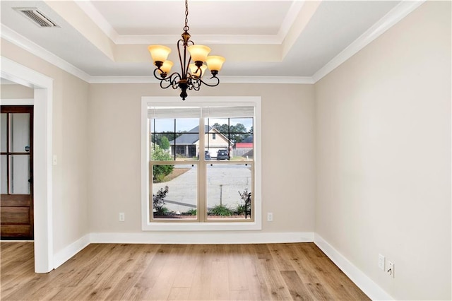 unfurnished dining area featuring light hardwood / wood-style flooring, an inviting chandelier, a tray ceiling, and ornamental molding