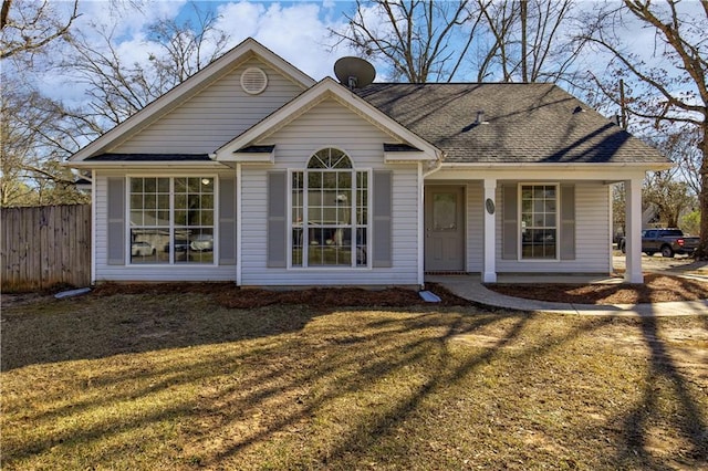 view of front of house featuring a shingled roof, fence, and a front lawn