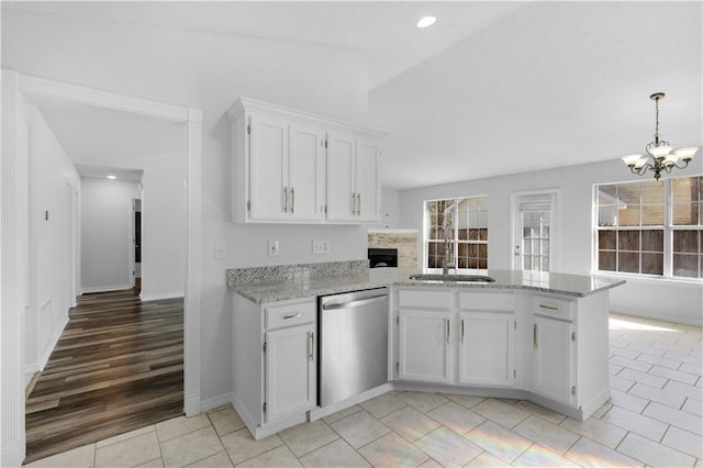 kitchen with dishwasher, light stone counters, a peninsula, white cabinetry, and a sink