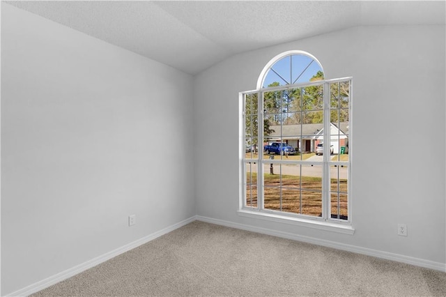 unfurnished room with lofted ceiling, carpet, baseboards, and a textured ceiling