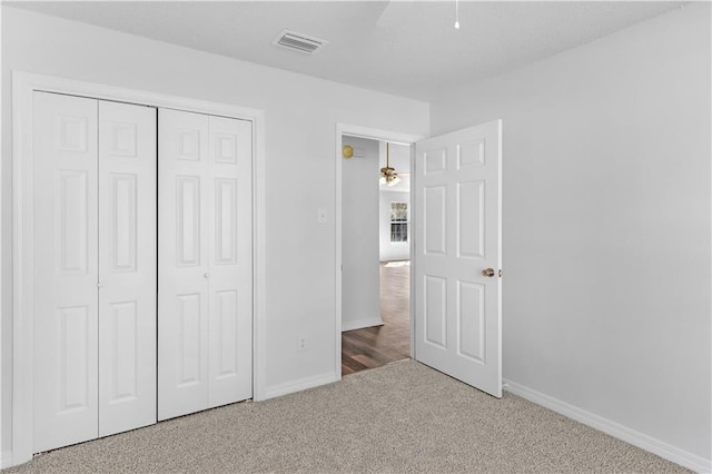 unfurnished bedroom with carpet floors, baseboards, visible vents, and a closet