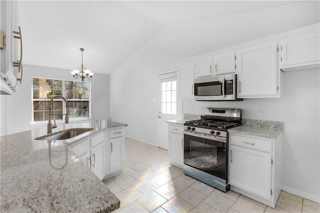 kitchen featuring appliances with stainless steel finishes, light stone countertops, vaulted ceiling, white cabinetry, and a sink