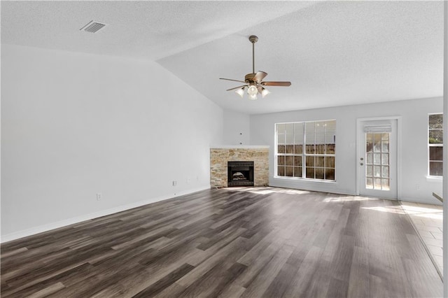 unfurnished living room with a fireplace, visible vents, a ceiling fan, vaulted ceiling, and dark wood-style floors