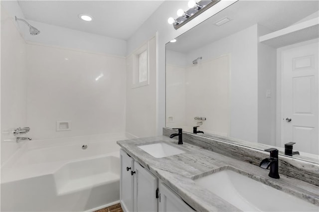 bathroom featuring visible vents, double vanity, a sink, and washtub / shower combination