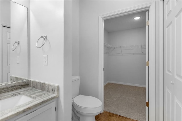 bathroom featuring tile patterned flooring, vanity, toilet, and a spacious closet