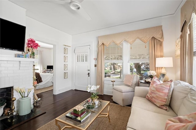 living room featuring ceiling fan, a fireplace, and dark hardwood / wood-style flooring