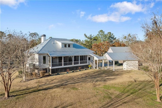 rear view of property featuring a carport, a sunroom, and a yard