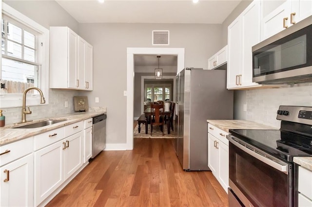 kitchen with visible vents, a sink, white cabinetry, stainless steel appliances, and light wood-style floors