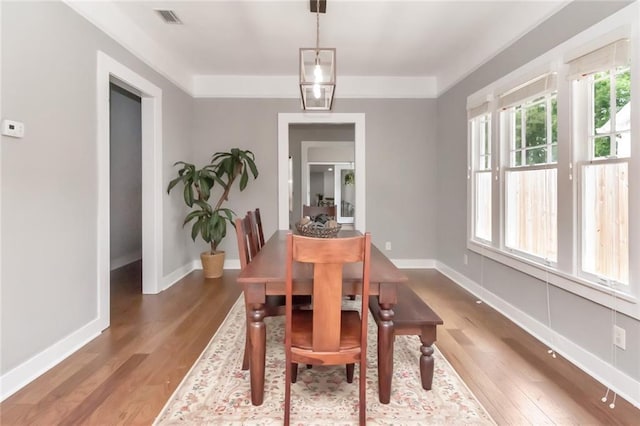 dining space with visible vents, wood finished floors, and baseboards