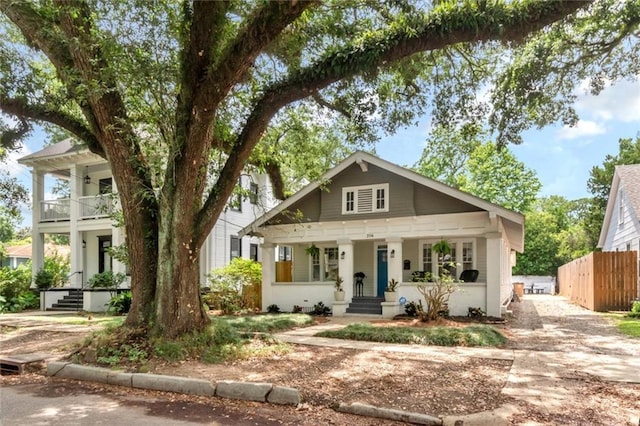 view of front of home featuring a balcony, fence, and covered porch