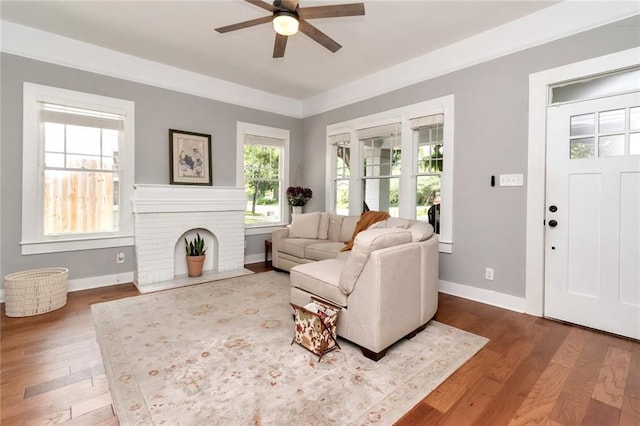 living room with a brick fireplace, baseboards, and wood finished floors