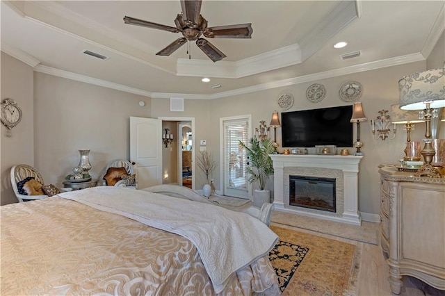 bedroom featuring crown molding, a fireplace, a raised ceiling, and ceiling fan