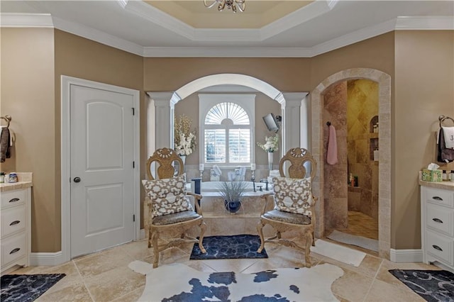 bathroom with ornate columns, vanity, ornamental molding, tiled shower, and a raised ceiling