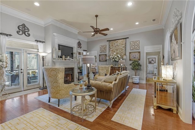 living room with hardwood / wood-style flooring, ceiling fan, and ornamental molding