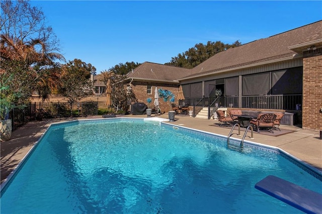 view of swimming pool featuring a patio, a diving board, a sunroom, and an outdoor fire pit