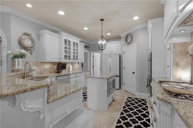 kitchen with appliances with stainless steel finishes, sink, a kitchen island, and white cabinets