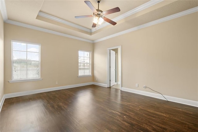 unfurnished room with ornamental molding, ceiling fan, dark wood-type flooring, and a tray ceiling