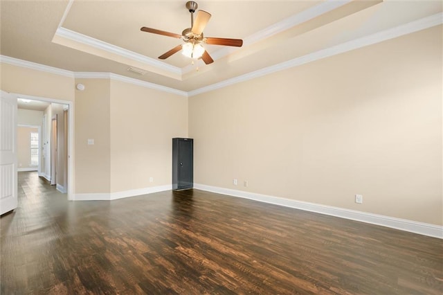 unfurnished room with ornamental molding, dark wood-type flooring, ceiling fan, and a tray ceiling