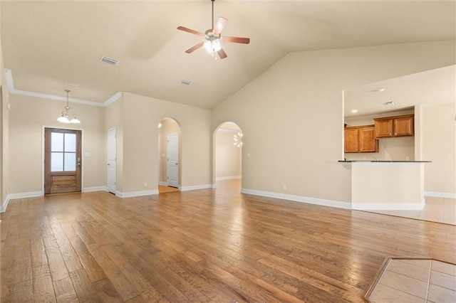 unfurnished living room with ceiling fan with notable chandelier, high vaulted ceiling, ornamental molding, and hardwood / wood-style flooring