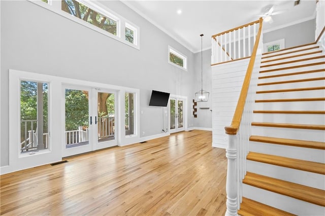 interior space featuring ornamental molding, light hardwood / wood-style flooring, plenty of natural light, and a high ceiling