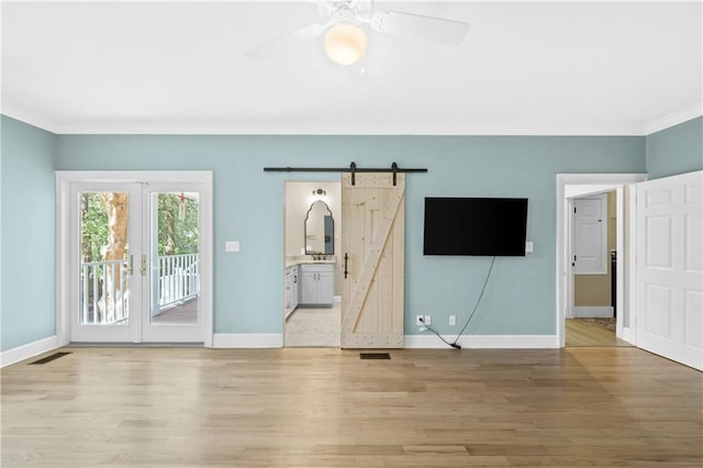 interior space featuring light hardwood / wood-style flooring, ceiling fan, crown molding, and a barn door