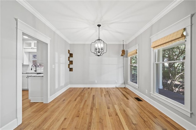 unfurnished dining area featuring light wood-type flooring, crown molding, and a chandelier