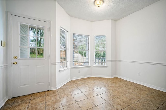 foyer entrance with plenty of natural light, a textured ceiling, and light tile patterned floors