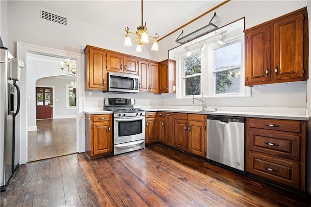 kitchen with an inviting chandelier, pendant lighting, dark hardwood / wood-style flooring, and appliances with stainless steel finishes