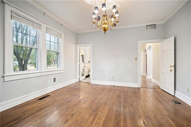 spare room featuring a notable chandelier, ornamental molding, and hardwood / wood-style floors