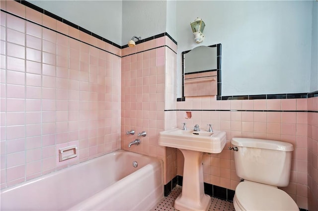 bathroom with tiled shower / bath combo, tile walls, and toilet