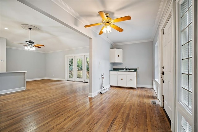 unfurnished living room with sink, crown molding, and light hardwood / wood-style flooring