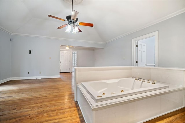 bathroom featuring hardwood / wood-style flooring, ornamental molding, vaulted ceiling, and a bathtub