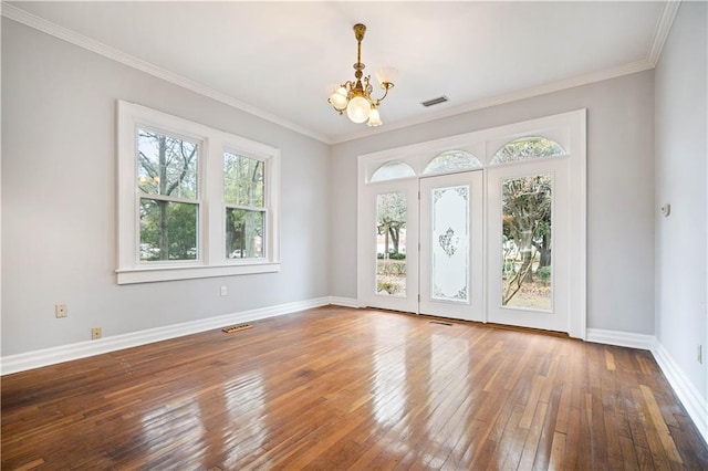 empty room featuring hardwood / wood-style flooring, ornamental molding, and a chandelier