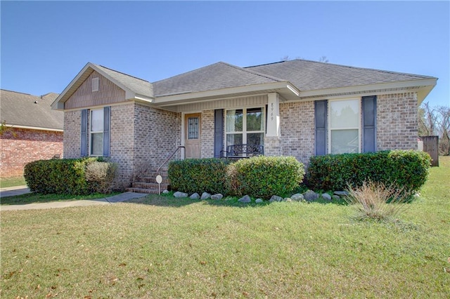 ranch-style house with a front yard, covered porch, brick siding, and roof with shingles