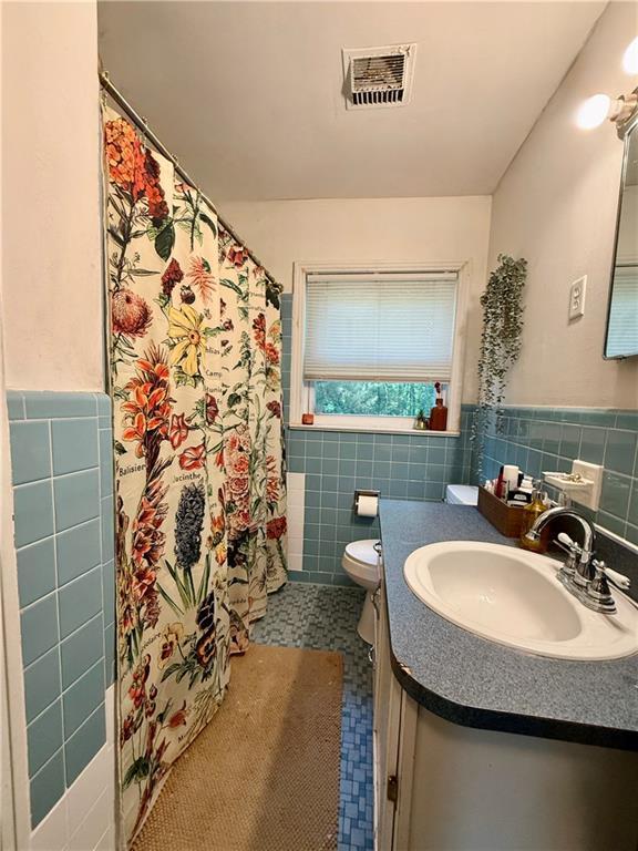 7020 Moffett Rd, Mobile, AL 36618 - full bath with tile walls, toilet, vanity, wainscoting, and tile patterned floors