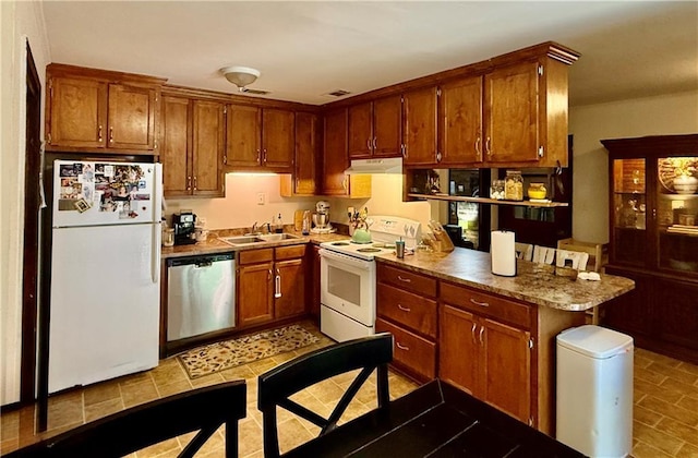 7020 Moffett Rd, Mobile, AL 36618 - kitchen with white appliances, under cabinet range hood, a sink, and brown cabinets