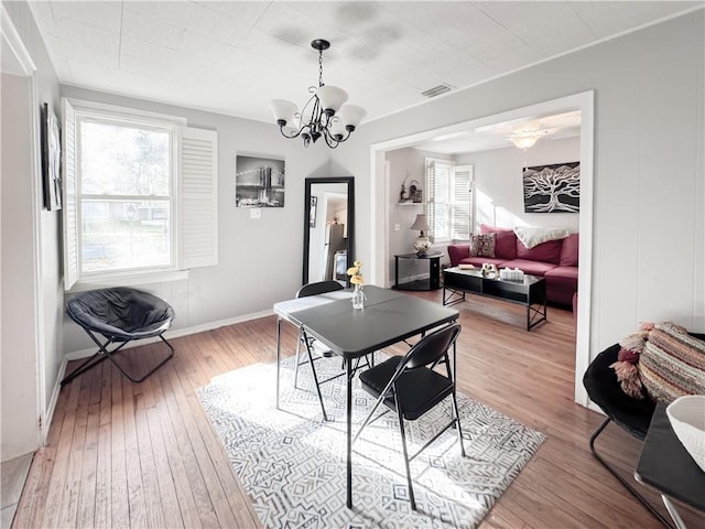 dining area featuring light wood-type flooring, visible vents, baseboards, and an inviting chandelier