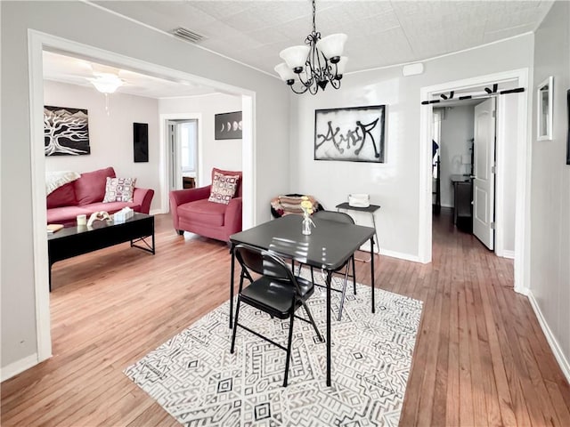 dining space with visible vents, baseboards, a notable chandelier, and wood finished floors