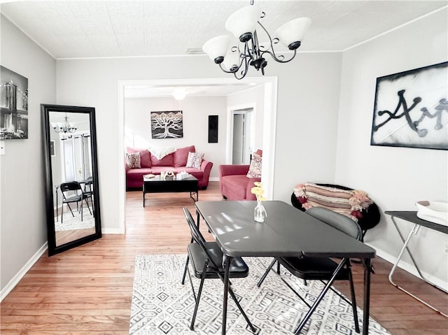 dining room featuring a notable chandelier, baseboards, and light wood finished floors