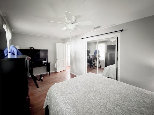 bedroom with visible vents, a ceiling fan, wood finished floors, a closet, and baseboards