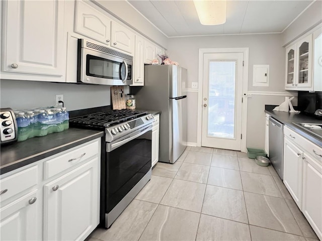 kitchen featuring dark countertops, white cabinets, appliances with stainless steel finishes, and glass insert cabinets