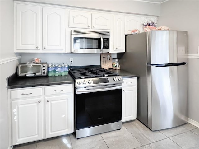 kitchen featuring white cabinetry, dark countertops, a toaster, and appliances with stainless steel finishes